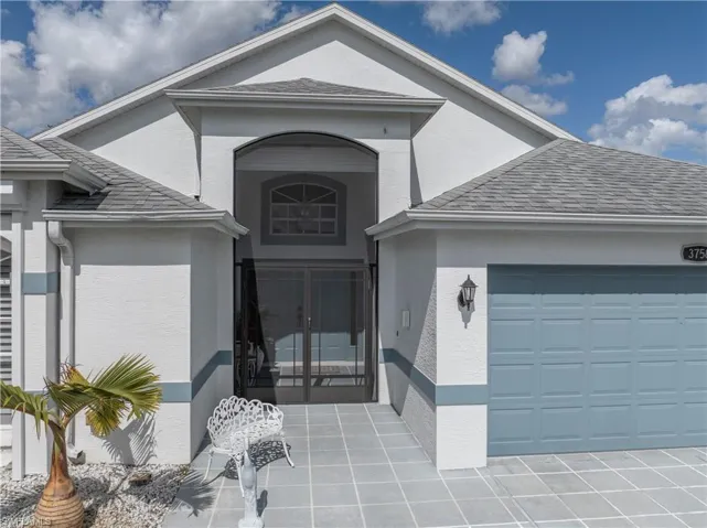 View of exterior entry with french doors, stucco siding, a garage, and roof with shingles