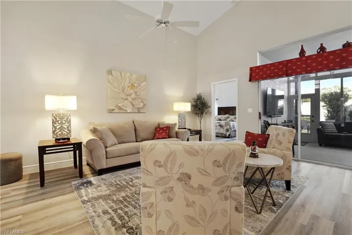 Living room with high vaulted ceiling, light wood finished floors, and ceiling fan