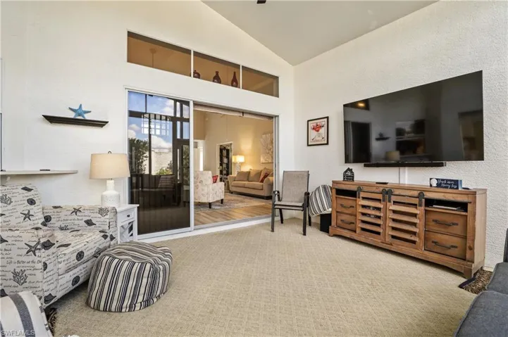 Living room with a textured wall, vaulted ceiling, and carpet