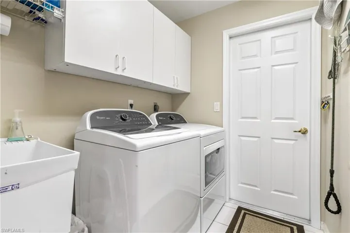 Laundry room with tile patterned flooring, separate washer and dryer, and cabinet space