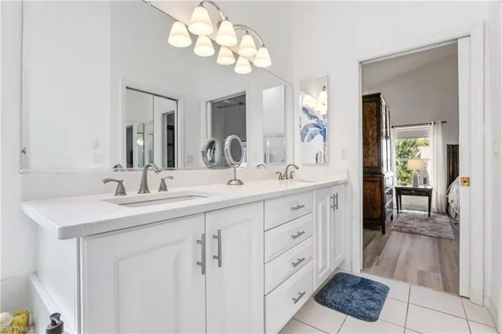 Full bathroom with light tile patterned floors, double vanity, and ensuite bathroom