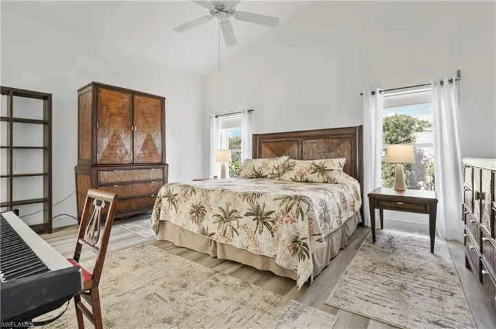 Bedroom with high vaulted ceiling, wood finished floors, and ceiling fan