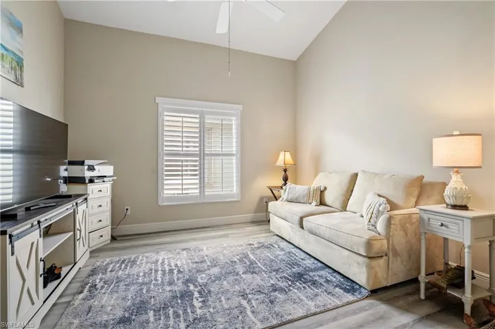 Living area with light wood-style flooring, a ceiling fan, and lofted ceiling