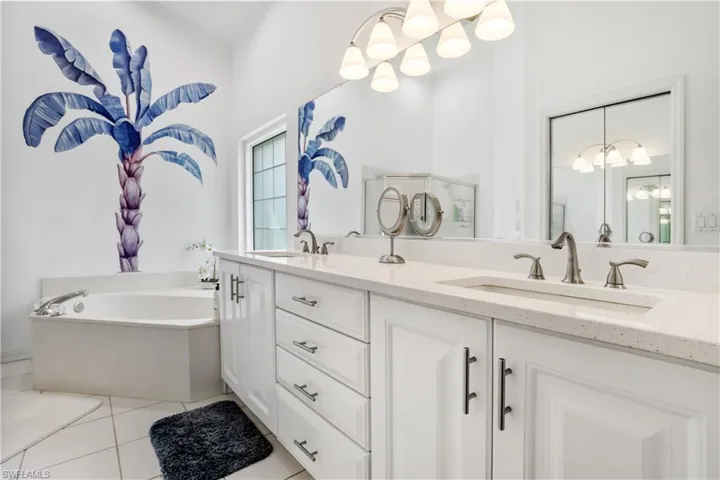 Full bathroom featuring light tile patterned floors, double vanity, and a garden tub