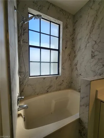 Bathroom featuring vanity and a combined bath / shower with marble appearance