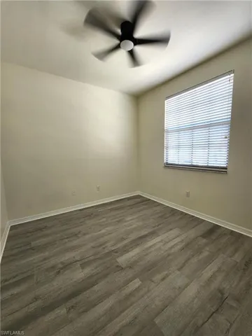 Unfurnished room with a ceiling fan and dark wood-style floors