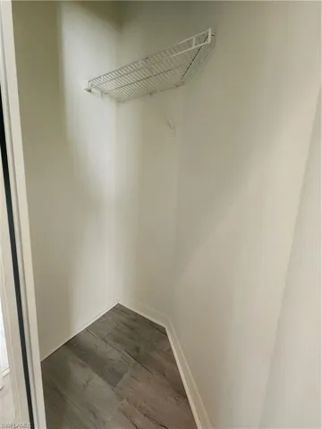 Walk in closet with dark wood-style floors