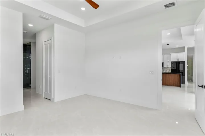 Empty room with light tile patterned floors, a raised ceiling, and ceiling fan