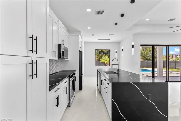 Kitchen with sink, light tile patterned floors, white cabinets, and pendant lighting