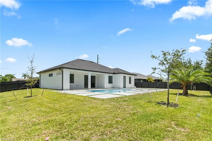 Rear view of property with a patio area, a fenced in pool, and a yard