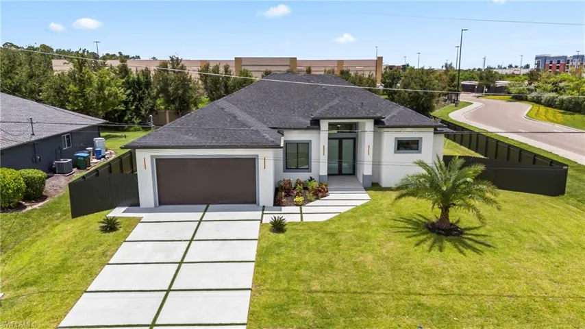 View of front of home featuring a garage, central AC, and a front yard