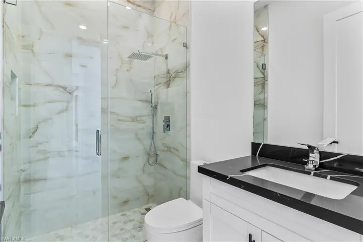 Bathroom featuring vanity, an enclosed shower, and toilet