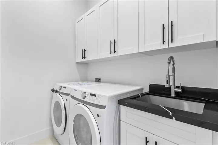 Clothes washing area with sink, separate washer and dryer, and cabinets