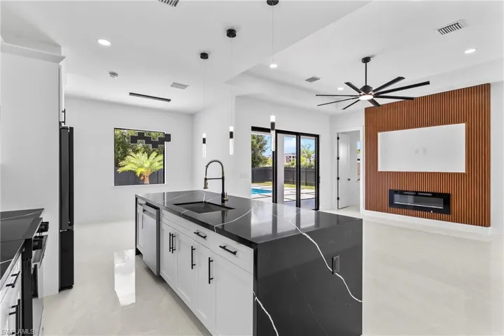 Kitchen featuring white cabinetry, ceiling fan, pendant lighting, sink, and light tile patterned floors