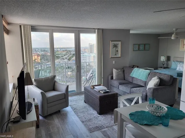 Living room with a textured ceiling, hardwood / wood-style floors, ceiling fan, and a city view
