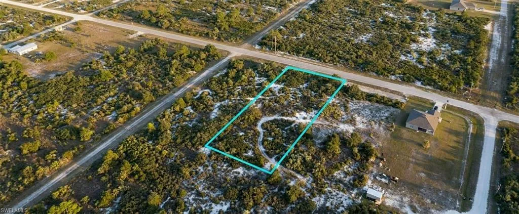 Expansive undeveloped lot featuring natural vegetation, a sandy ground cover, and frontage on two distinct roadways