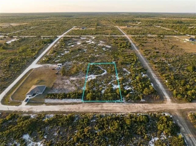 Expansive vacant land parcel, outlined in blue, featuring natural scrub brush and sandy terrain