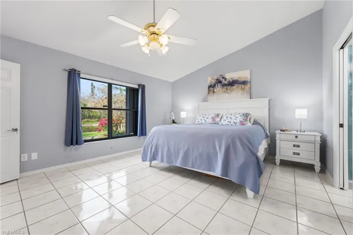 Tiled bedroom featuring ceiling fan and vaulted ceiling