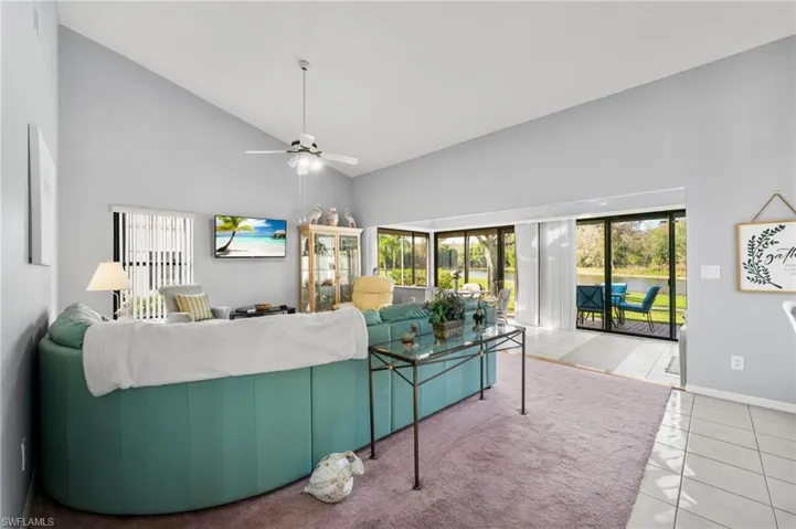 Tiled living room featuring ceiling fan and high vaulted ceiling