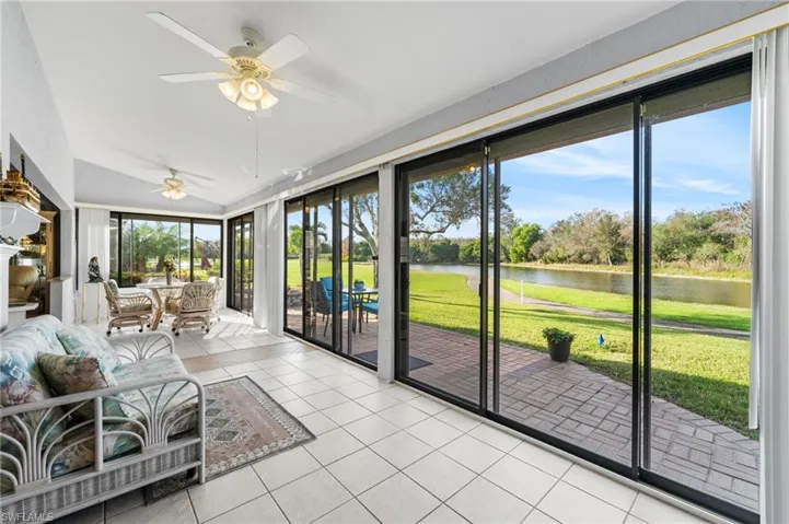 sunroom featuring ceiling fan and a water view