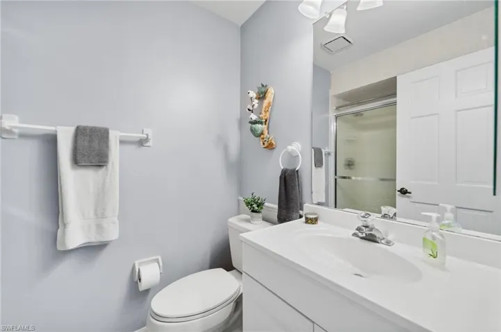Bathroom with vanity, toilet, and a shower with shower door