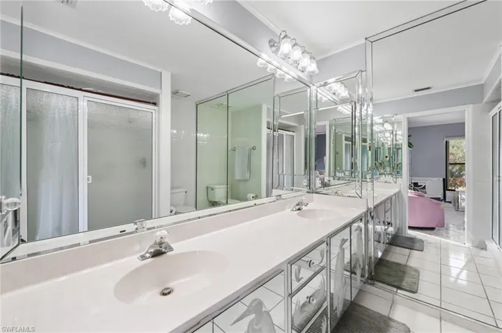 Bathroom featuring toilet, vanity, tile patterned floors, and an enclosed shower