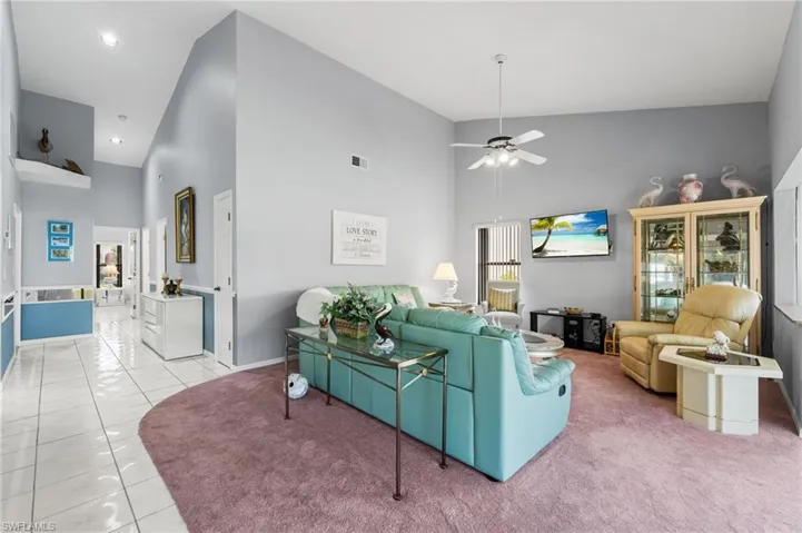 Living room featuring ceiling fan, light tile patterned flooring, and high vaulted ceiling