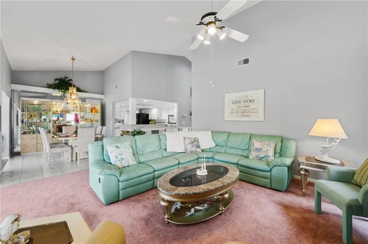 Living room with light carpet, high vaulted ceiling, and ceiling fan