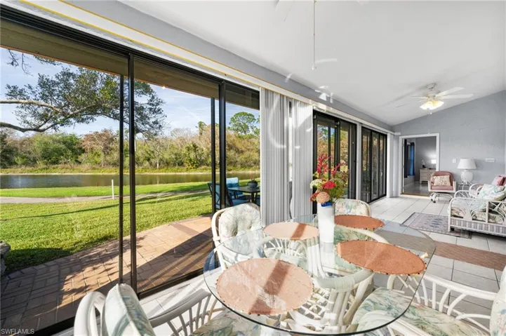 Sunroom with ceiling fan, a water view, and lofted ceiling