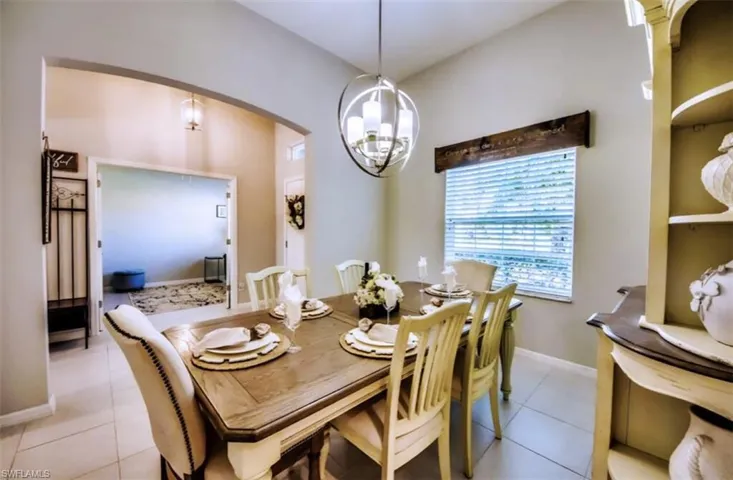 Dining area with light tile patterned flooring, arched walkways, and a chandelier