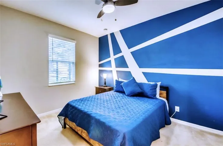 Bedroom with carpet flooring, an accent wall, and a ceiling fan