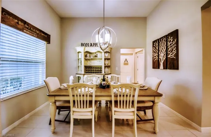 Tiled dining area featuring a chandelier and baseboards