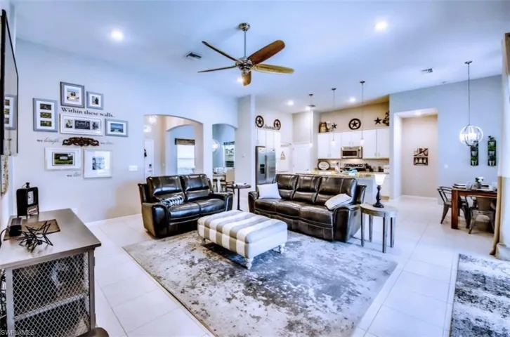 Living area featuring arched walkways, ceiling fan, recessed lighting, light tile patterned floors, and a chandelier