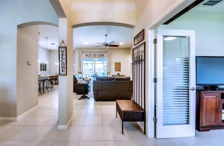Living area with ceiling fan, arched walkways, light tile patterned flooring, and recessed lighting