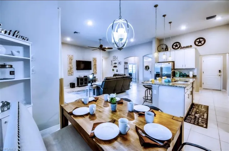 Dining space with arched walkways, ceiling fan, light tile patterned floors, and recessed lighting