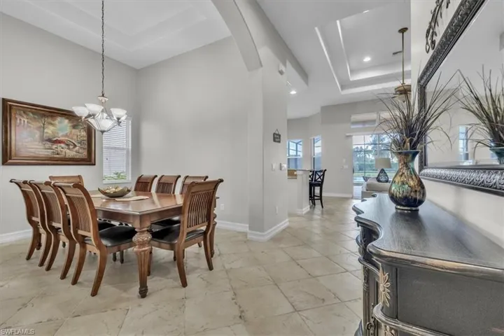 Dining room with a raised ceiling, arched walkways, a chandelier, and recessed lighting