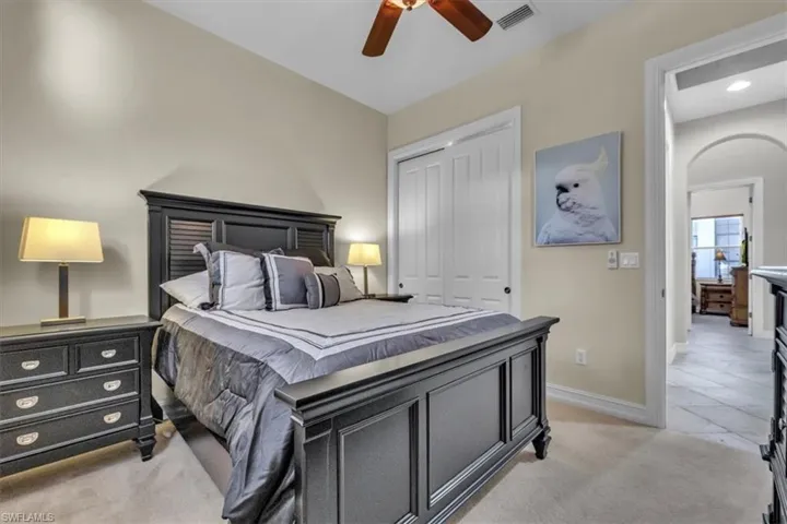 Bedroom with light carpet, a closet, a ceiling fan, and arched walkways