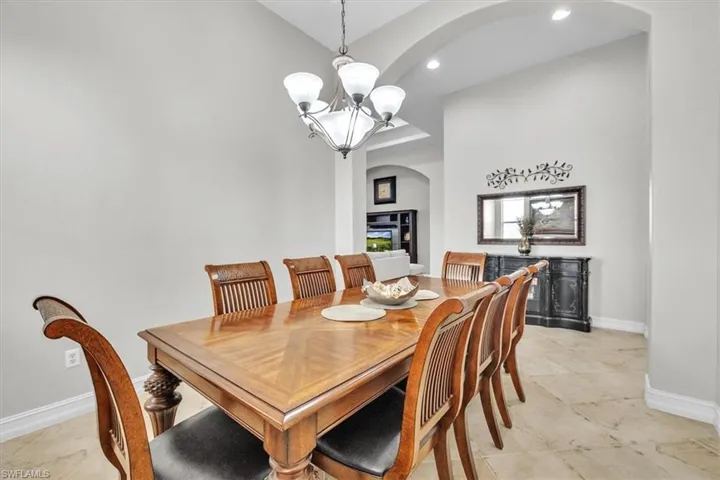 Dining area with arched walkways, a chandelier, and recessed lighting