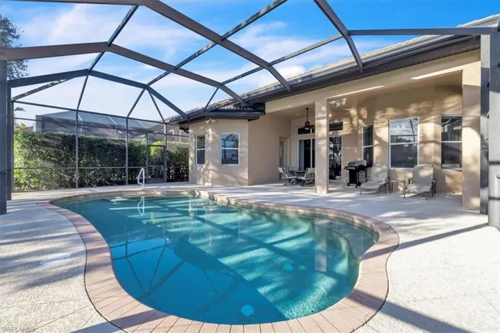 Swimming pool with a sunroom, glass enclosure, a patio, and area for grilling