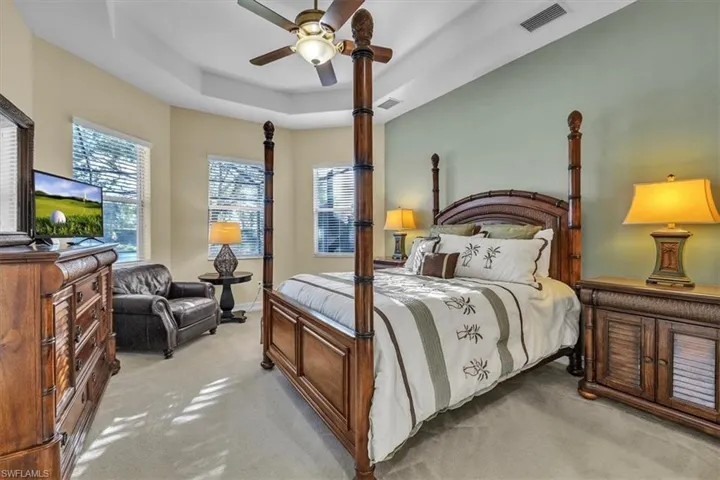 Master Bedroom Suite with a tray ceiling, light carpet, and a ceiling fan