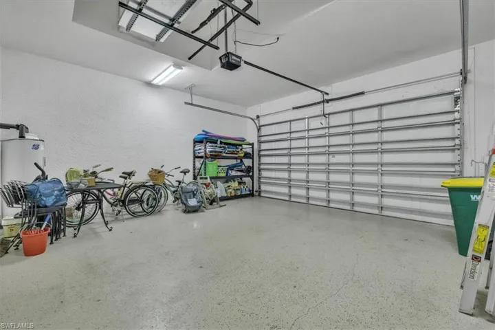 Garage with a textured wall, water heater, and a garage door opener