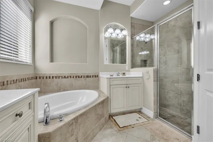 Bathroom featuring vanity, a bath, a stall shower, and light tile patterned floors