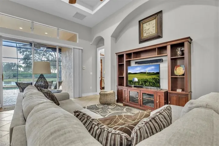 Living room with arched walkways, ceiling fan, light tile patterned floors, and a high ceiling