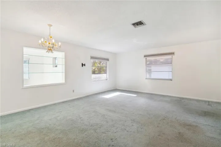 Spare room with carpet flooring, a chandelier, and a textured ceiling