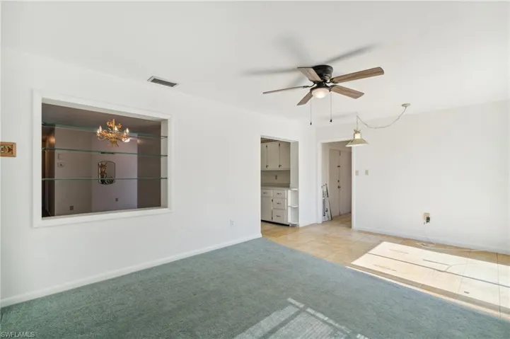Empty room with light carpet, a ceiling fan, and light tile patterned floors
