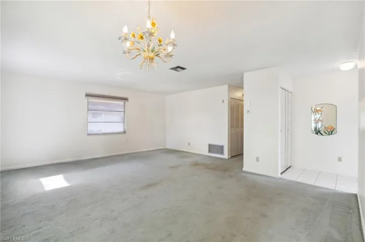 Empty room featuring carpet floors and a chandelier