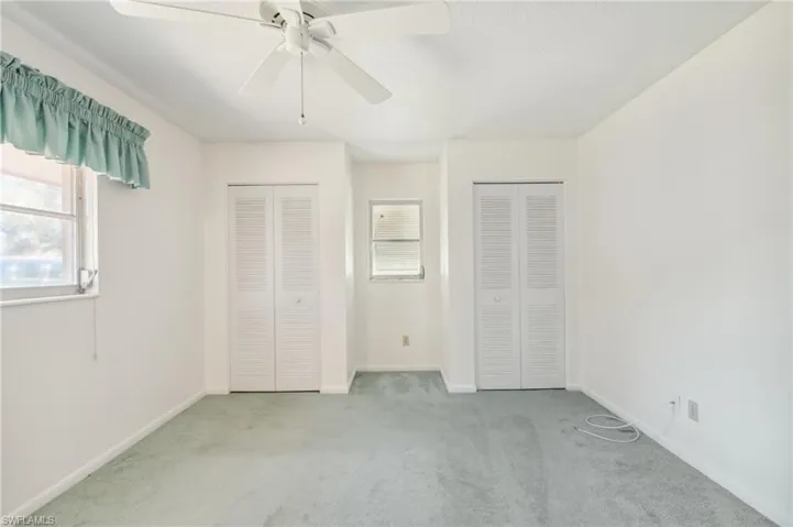 Unfurnished bedroom with carpet flooring, two closets, and ceiling fan
