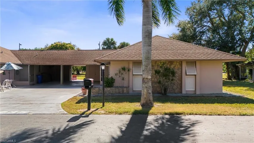Ranch-style house featuring a front yard, a carport, concrete driveway, and stucco siding