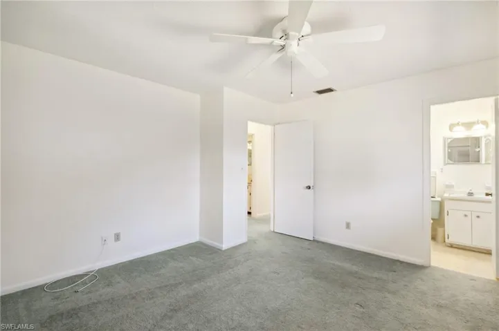 Unfurnished bedroom featuring carpet, a ceiling fan, and ensuite bath