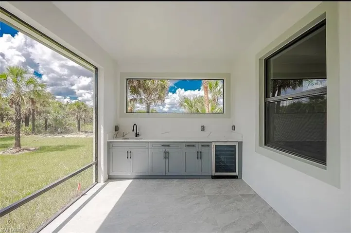 Unfurnished sunroom with wine cooler and indoor wet bar